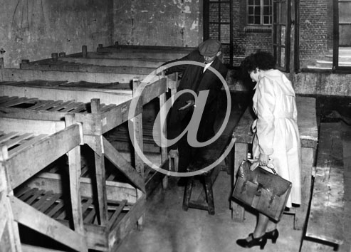 inconnu() Anne 1945- Libration - 140205 Une femme se fait expliquer les conditions de couchage par un guide qui lui montre les couchettes superposes dans une baraque.