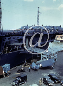 inconnu() Seconde guerre mondiale US Navy en couleurs - Srie 80-GK- : Voitures, avion dmont, petit tracteur et autres vhicules sur le quai duquel on a jet une passerelle sur un porte avion. Noter l